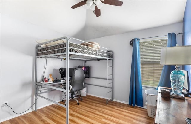 bedroom featuring baseboards, multiple windows, a ceiling fan, vaulted ceiling, and wood finished floors