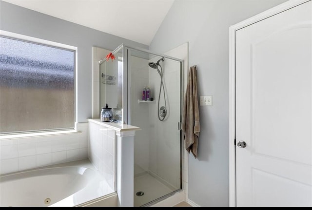 bathroom with a shower stall, lofted ceiling, and a tub with jets