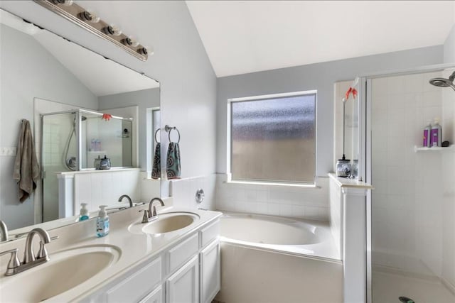 full bathroom with a stall shower, double vanity, a sink, and vaulted ceiling
