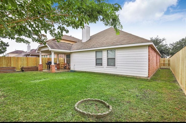 rear view of house with a yard, a fenced backyard, a chimney, and a patio area
