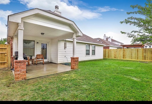 rear view of house with a patio, fence, and a lawn