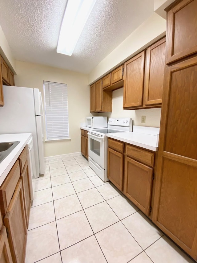 10555 Turtlewood Ct Unit 2102, Houston, TX 77072 - kitchen featuring light tile patterned floors, light countertops, white appliances, a textured ceiling, and brown cabinetry