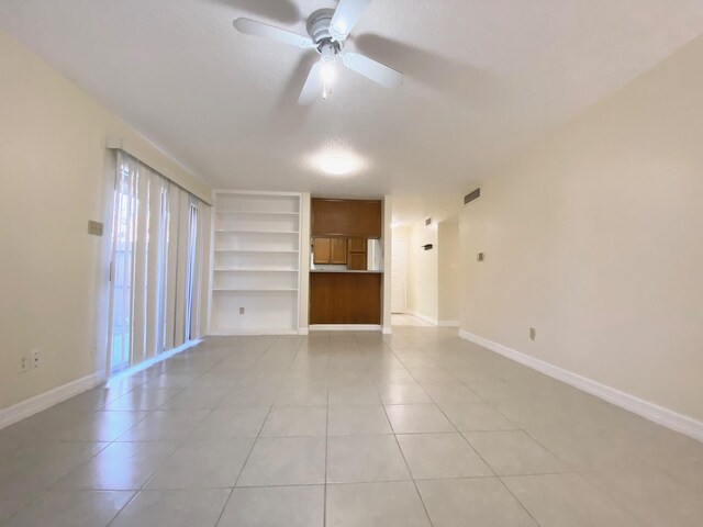 10555 Turtlewood Ct Unit 2102, Houston, TX 77072 - unfurnished living room featuring built in shelves, ceiling fan, baseboards, and light tile patterned flooring