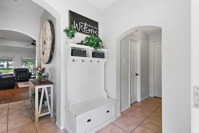 mudroom with arched walkways, light tile patterned floors, and a ceiling fan