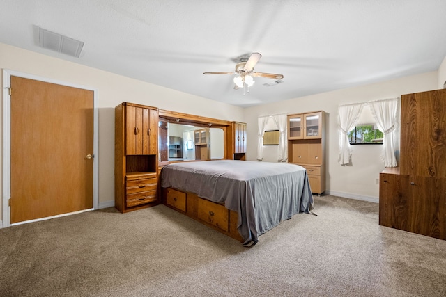 bedroom with baseboards, visible vents, a ceiling fan, and light colored carpet