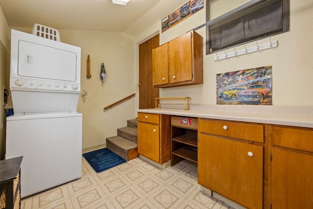 washroom with cabinet space, stacked washing maching and dryer, and light floors