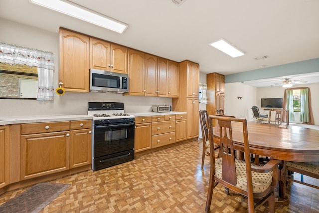 kitchen featuring light countertops, visible vents, stainless steel microwave, gas stove, and ceiling fan