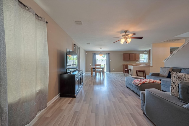 living area with a ceiling fan, visible vents, plenty of natural light, and light wood finished floors