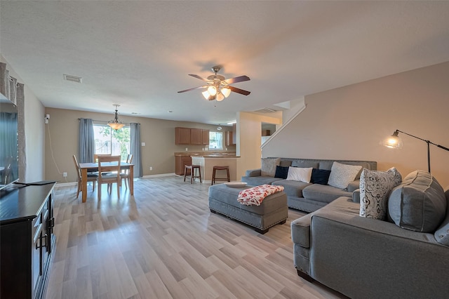 living room with visible vents, light wood-style flooring, ceiling fan, and baseboards