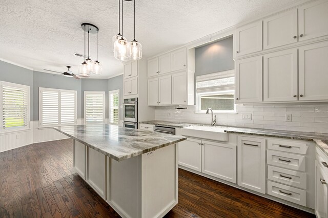 5511 Oak Cove Dr, Kingwood, TX 77345 - kitchen with a sink, a textured ceiling, dark wood finished floors, white cabinetry, and a kitchen island