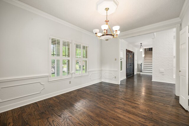 5511 Oak Cove Dr, Kingwood, TX 77345 - empty room with dark wood finished floors, wainscoting, an inviting chandelier, stairway, and crown molding