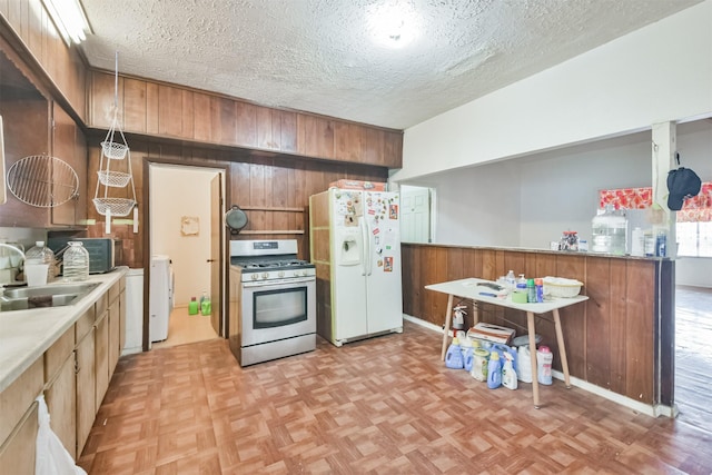 7846 Dayton St, Houston, TX 77012 - kitchen featuring washer / clothes dryer, stainless steel gas range, wooden walls, white refrigerator with ice dispenser, and a sink