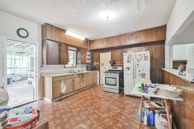 7846 Dayton St, Houston, TX 77012 - kitchen with white fridge with ice dispenser, light countertops, stainless steel gas range, a textured ceiling, and wood walls