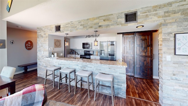 12500 Melville Dr Unit 211, Montgomery, TX 77356 - kitchen featuring stainless steel appliances, a peninsula, a breakfast bar area, white cabinetry, and dark wood finished floors