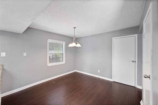 unfurnished room with a chandelier, dark wood-style floors, baseboards, and a textured ceiling