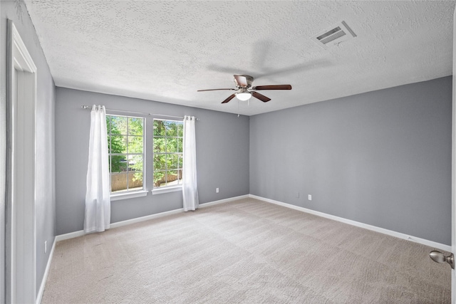 empty room with visible vents, a textured ceiling, baseboards, and ceiling fan
