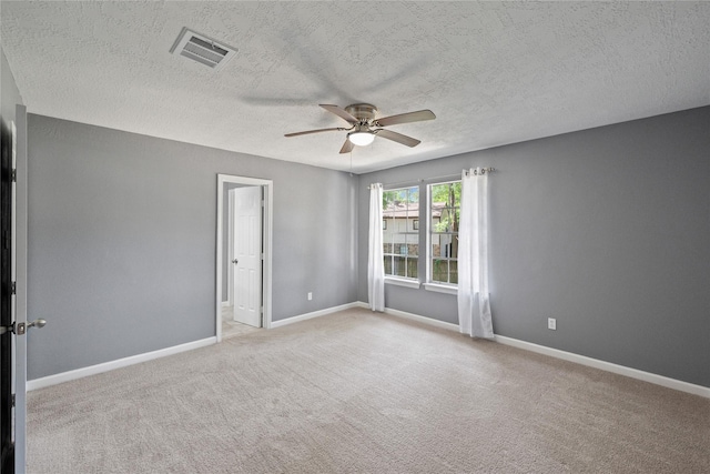 carpeted spare room featuring visible vents, baseboards, a ceiling fan, and a textured ceiling