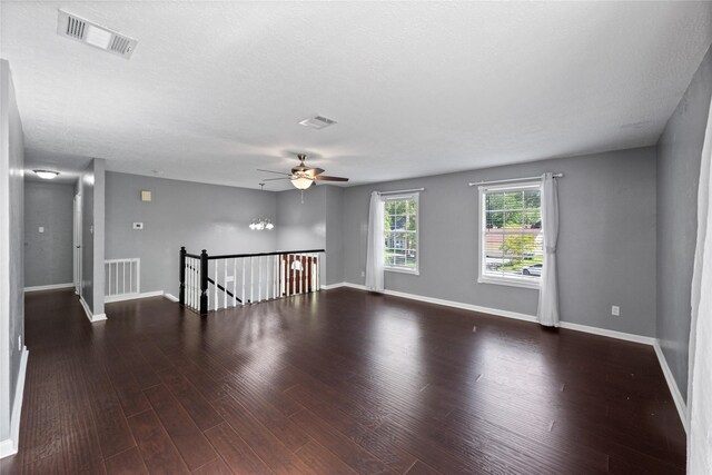 empty room featuring wood finished floors, ceiling fan, baseboards, and visible vents