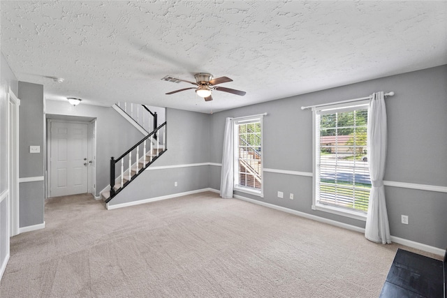 unfurnished living room with baseboards, a ceiling fan, carpet flooring, and stairs