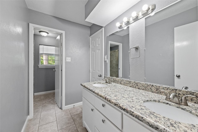 full bathroom featuring tile patterned floors, double vanity, a sink, and baseboards