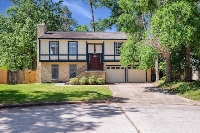 split foyer home with an attached garage, a chimney, fence, concrete driveway, and brick siding
