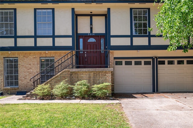view of front of home with concrete driveway, brick siding, stucco siding, and an attached garage