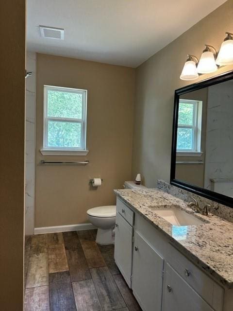 bathroom with vanity, visible vents, wood finished floors, toilet, and baseboards