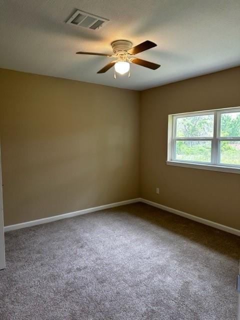 carpeted empty room featuring baseboards, ceiling fan, and visible vents