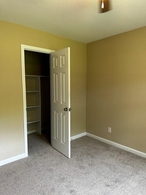 unfurnished bedroom featuring a closet, carpet, baseboards, and a spacious closet