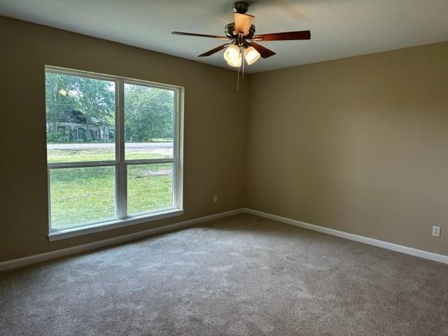 carpeted spare room with baseboards and ceiling fan