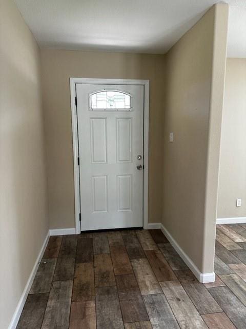 doorway featuring dark wood-style flooring and baseboards