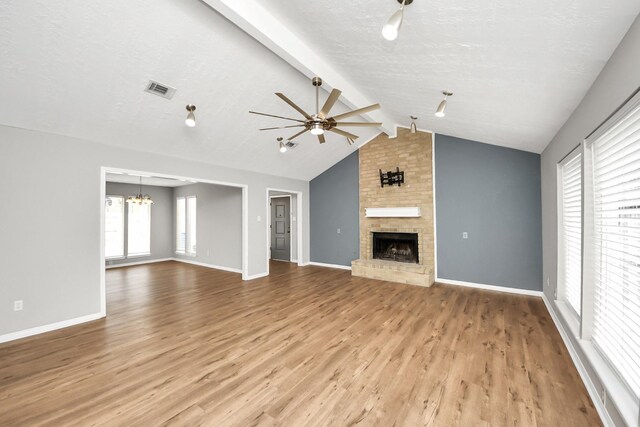619 Shenandoah Dr, Shenandoah, TX 77381 - unfurnished living room featuring a fireplace, visible vents, ceiling fan with notable chandelier, vaulted ceiling with beams, and wood finished floors