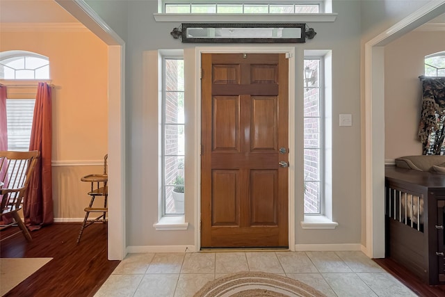 entryway with ornamental molding and baseboards