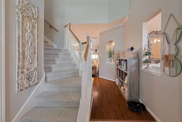 staircase with baseboards, arched walkways, and wood finished floors