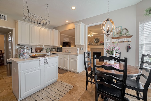 kitchen with decorative light fixtures, a sink, light countertops, and white cabinets