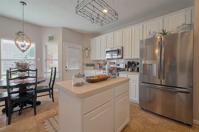 kitchen with an inviting chandelier, white cabinetry, a kitchen island, light countertops, and stainless steel appliances