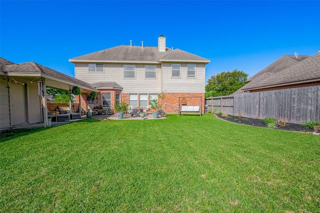 back of property with a fenced backyard, a lawn, a patio, brick siding, and a chimney