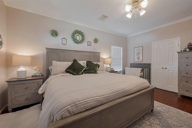 bedroom featuring crown molding, visible vents, a closet, and dark wood finished floors