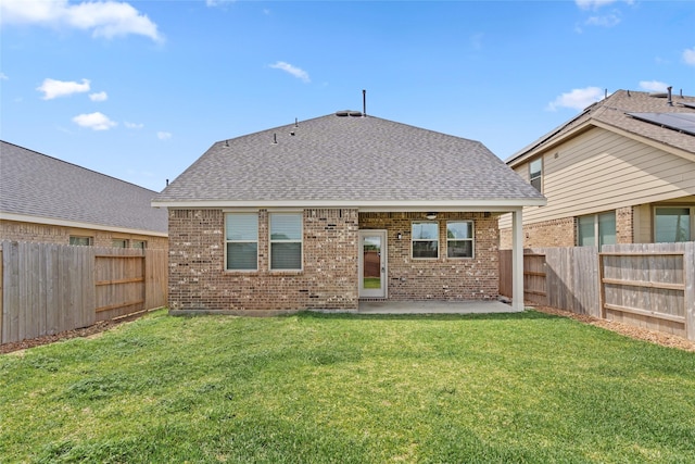 rear view of property with a yard, a fenced backyard, a patio, brick siding, and a shingled roof