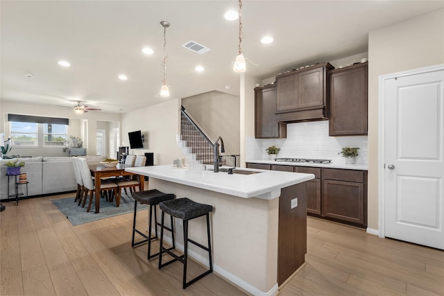 kitchen featuring tasteful backsplash, light wood-type flooring, ceiling fan, and dark brown cabinetry