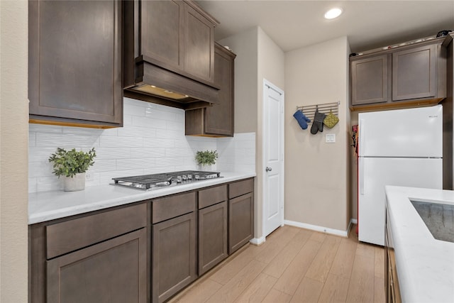 kitchen featuring light countertops, freestanding refrigerator, stainless steel gas stovetop, and decorative backsplash