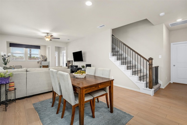 dining area featuring a ceiling fan, visible vents, stairs, light wood finished floors, and baseboards