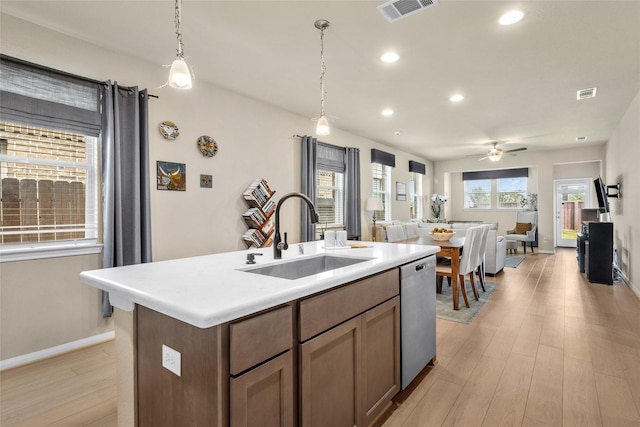 kitchen with stainless steel dishwasher, light wood-style flooring, visible vents, a sink, and open floor plan
