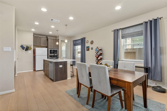 dining space featuring light wood-style floors, visible vents, baseboards, and plenty of natural light