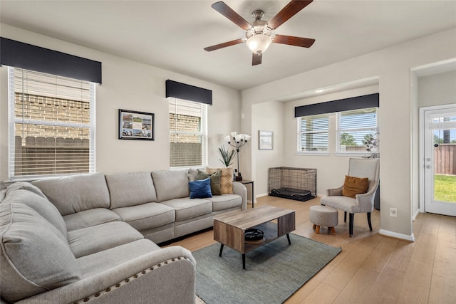 living room with light wood-style flooring, ceiling fan, and baseboards
