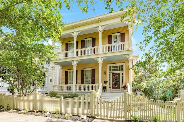 view of front of house with a porch, a balcony, and a fenced front yard