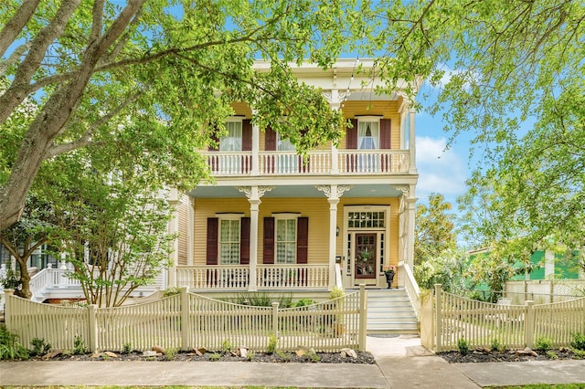view of front of home featuring a balcony, a fenced front yard, and covered porch