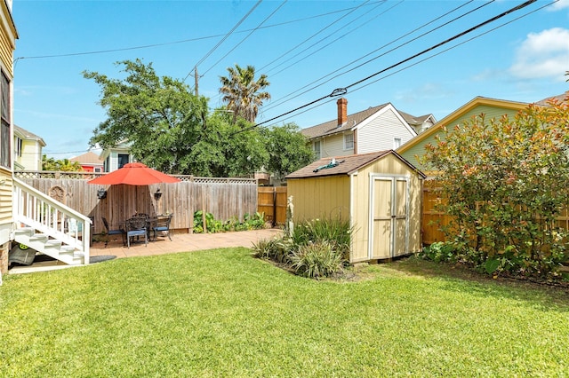 view of yard featuring a patio, a fenced backyard, an outbuilding, and a storage unit