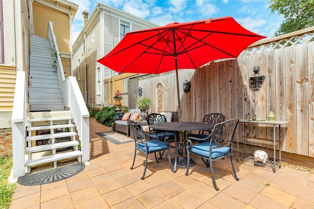 view of patio / terrace with fence, outdoor dining area, and stairs