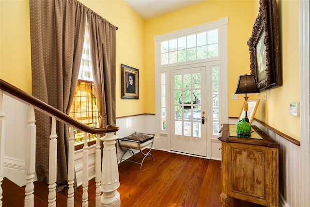 foyer featuring stairway, wood-type flooring, and a wainscoted wall